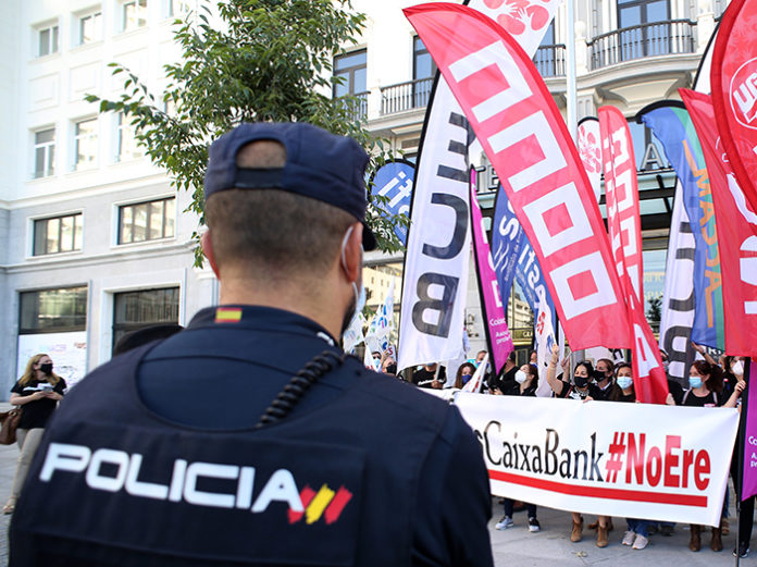 Un agente de Policía Nacional vigila a los trabajadores de CaixaBank durante el paro parcial convocado esta mañana en Madrid. Foto: Europa Press.