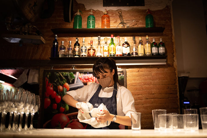 Una camarera seca unos vasos en un bar de Barcelona. Foto: Europa Press.