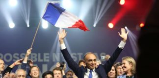 Éric Zemmour durante un mitin rodeado de personas y con una bandera de Francia.