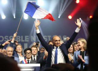 Éric Zemmour durante un mitin rodeado de personas y con una bandera de Francia.