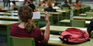 Un aula con alumnos realizando las pruebas de Selectividad (PAU) en mesas y sillas verdes.