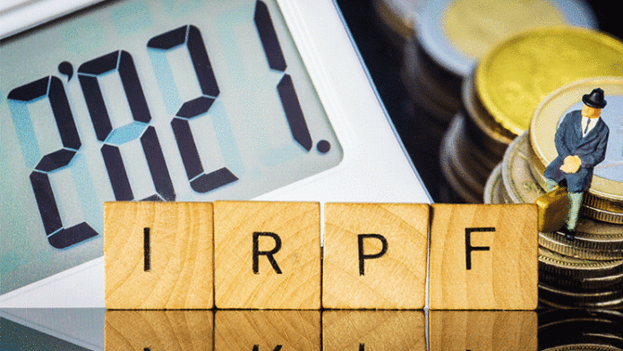 Detalle de una calculadora junto a unas fichas de madera con las letras de IRPF.
