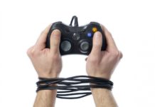 Mando de consola de videojuegos con las manos del usuario atadas por el cable, reflejando lo que es la adicción a internet