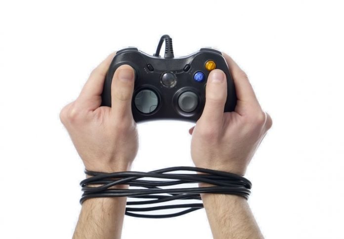 Mando de consola de videojuegos con las manos del usuario atadas por el cable, reflejando lo que es la adicción a internet