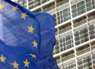 La UE empieza a cobrar una tasa de 3 euros a las compras baratas de Temu, Shein y AliExpress Bandera de la UE delante de un edificio comunitario.