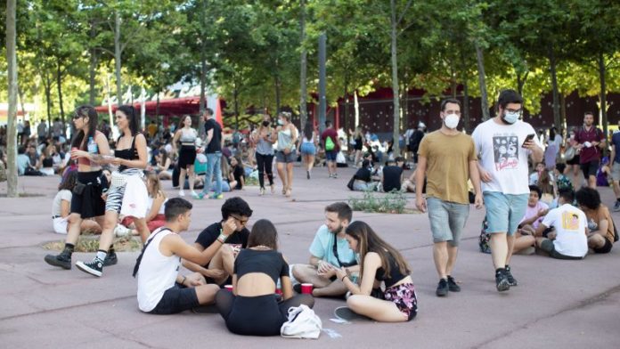 Un grupo de jóvenes sentados en el suelo en una calle de Barcelona.
