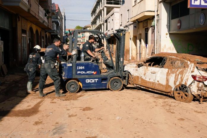 Policías nacionales retiran un vehículo en una calle llena de fango en Paiporta