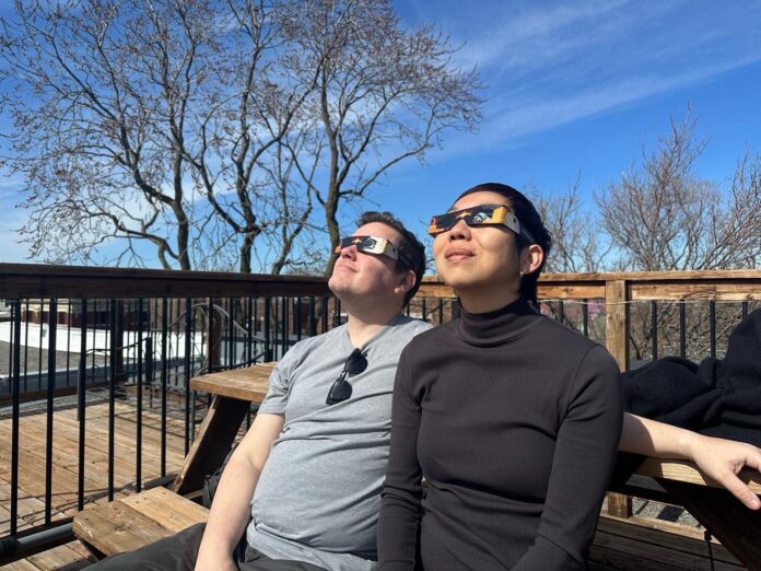 Un hombre y una mujer observan un eclipse de sol con unas gafas especiales.