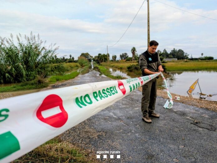 Vista de un miembro de Protecció Civil cerrando el acceso a una carretera.