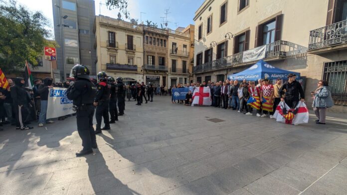 Mossos conteniendo a los atacantes y, a la derecha, los miembros de Aliança Catalana en la plaza Orfila del barrio de Sant Andreu.