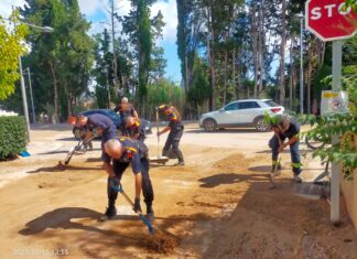 Voluntarios de Protección Civil retirando barro y tierra de una calle durante las tareas de limpieza tras las lluvias en Cataluña.