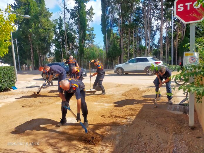 Voluntarios de Protección Civil retirando barro y tierra de una calle durante las tareas de limpieza tras las lluvias en Cataluña.