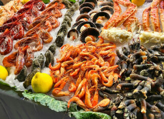 Mostrador de pescadería con diversos tipos de marisco fresco, incluyendo cangrejos y otros decápodos, bajo el hielo.