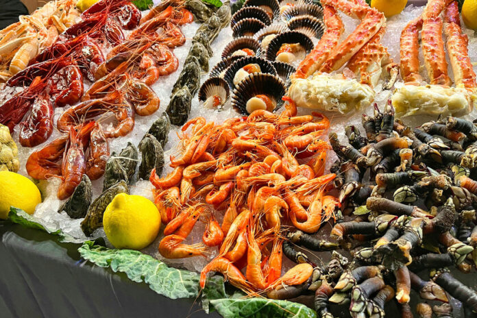 Mostrador de pescadería con diversos tipos de marisco fresco, incluyendo cangrejos y otros decápodos, bajo el hielo.