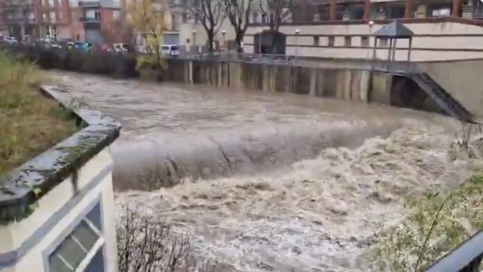 El río Fluvià con un gran caudal de agua marrón y turbulenta cruzando la ciudad de Olot durante la llevantada.
