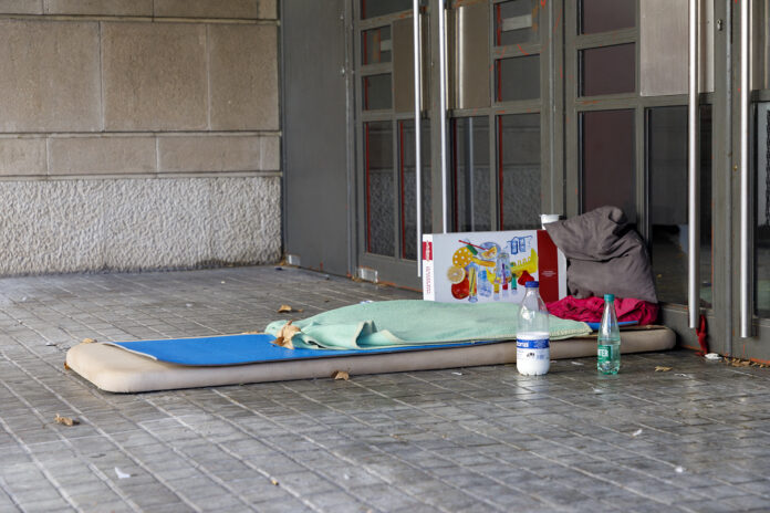 Una colchoneta y varios enseres en la acera y al lado de un portal.