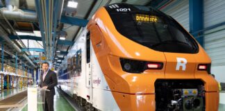 El ministro de Transportes, Óscar Puente, posa con un convoy de Rodalies a sus espaldas en Barcelona.