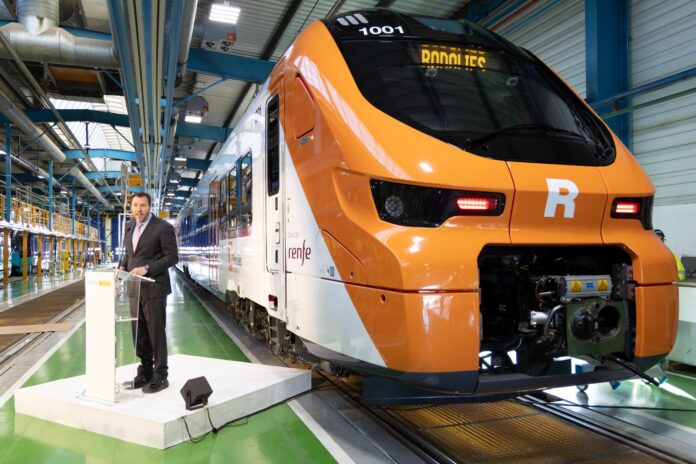 El ministro de Transportes, Óscar Puente, posa con un convoy de Rodalies a sus espaldas en Barcelona.