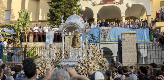 La Virgen de la Cinta rodeada de fieles en una calle de Huelva durante una procesión.