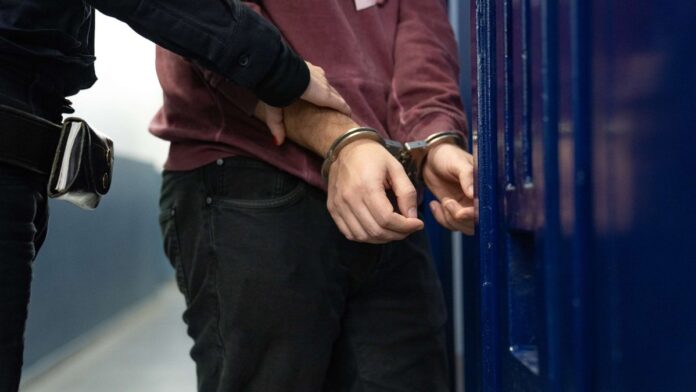 Un agente de los Mossos d'Esquadra custodia a un detenido esposado tras el desmantelamiento de una red criminal en Barcelona.