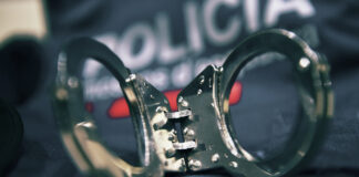 Primer plano de unas esposas metálicas sobre el uniforme oficial de los Mossos d'Esquadra en una actuación policial.