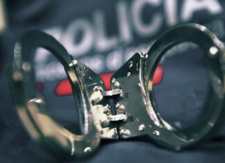 Primer plano de unas esposas metálicas sobre el uniforme oficial de los Mossos d'Esquadra en una actuación policial.