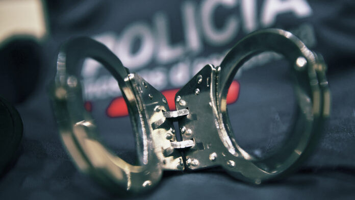 Primer plano de unas esposas metálicas sobre el uniforme oficial de los Mossos d'Esquadra en una actuación policial.