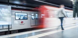 Vagón del metro de Barcelona con el logotipo de TMB circulando por una estación con pasajeros en el andén durante el Mobile World Congress.