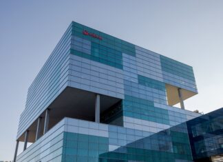Fachada exterior del edificio de la sede de Veolia en Barcelona, una estructura moderna de cristal y metal bajo un cielo despejado.