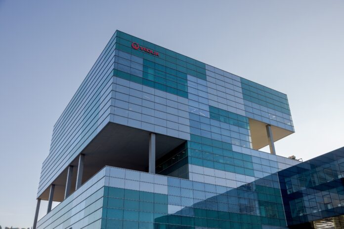 Fachada exterior del edificio de la sede de Veolia en Barcelona, una estructura moderna de cristal y metal bajo un cielo despejado.