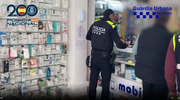 Agentes de la Policía Nacional y Guardia Urbana en una tienda de telefonía en Barcelona durante la operación contra la estafa del router.