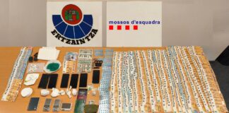 Mesa con fajos de billetes, envoltorios de droga, teléfonos móviles y básculas de precisión incautados en una operación policial.