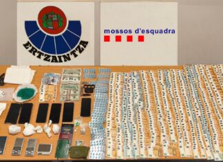 Mesa con fajos de billetes, envoltorios de droga, teléfonos móviles y básculas de precisión incautados en una operación policial.