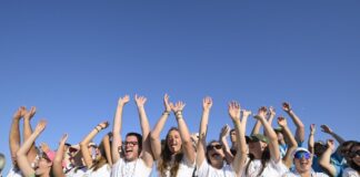 Un grup de joves a Tor Vergata, amb les mans aixecades en senyal d'alegria, darrere d'una tanca de seguretat, durant el Jubileu dels Joves.