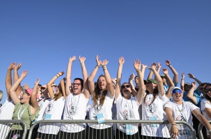 Un grup de joves a Tor Vergata, amb les mans aixecades en senyal d'alegria, darrere d'una tanca de seguretat, durant el Jubileu dels Joves.
