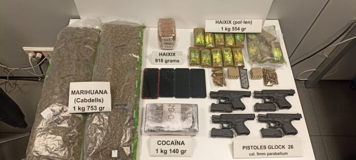 Arsenal incautado por los Mossos en La Mina con pistolas Glock, cocaína, hachís y marihuana sobre una mesa de evidencias.