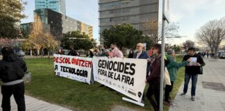 Un grupo reducido de personas sostiene pancartas con los lemas "Descolonitzem la tecnologia" y "Genocides fora de la Fira" en los exteriores del MWC.