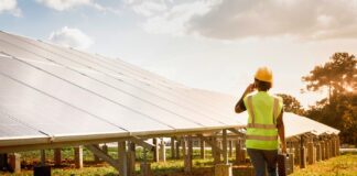 Una operaria técnica camina junto a una hilera de paneles solares en una planta fotovoltaica financiada por Banco Santander.