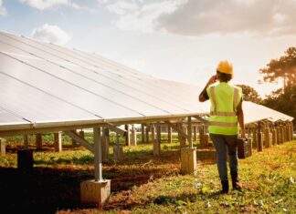 Una operaria técnica camina junto a una hilera de paneles solares en una planta fotovoltaica financiada por Banco Santander.