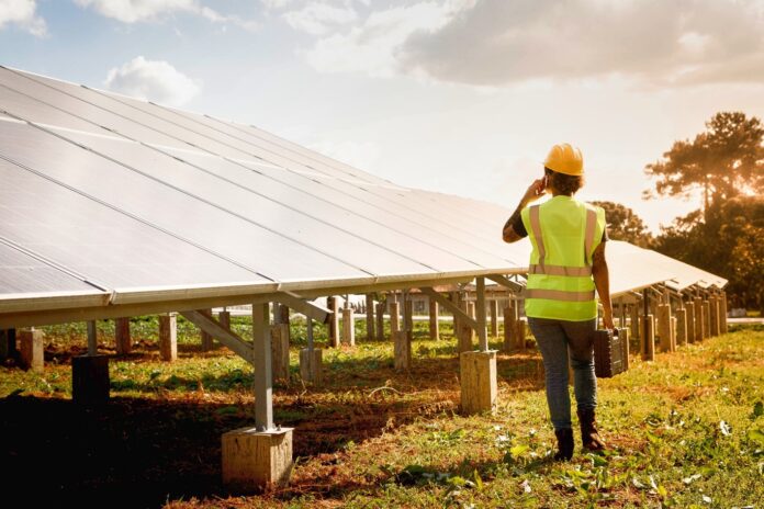 Una operaria técnica camina junto a una hilera de paneles solares en una planta fotovoltaica financiada por Banco Santander.
