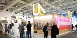 Vista general del stand de Cataluña en la Feria Internacional de Turisme de Berlín (ITB), con una gran fotografía aérea de Barcelona y profesionales del sector conversando.