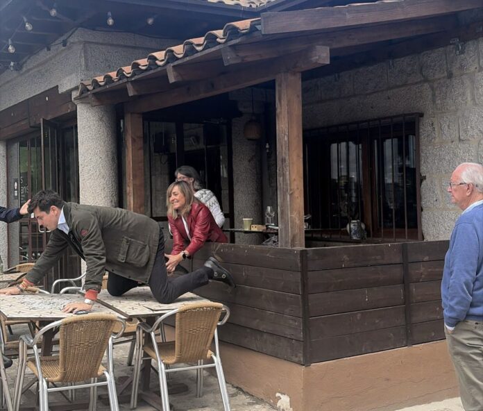 Vito Quiles sobre una mesa y detrás de él los acompañantes de Begoña Gómez.