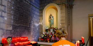 Interior de la iglesia de Sant Jaume en Barcelona con velas encendidas y una persona rezando