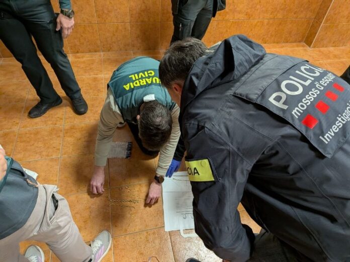 Agentes de los Mossos d'Esquadra y la Guardia Civil inspeccionan joyas robadas recuperadas en el suelo durante la operación contra la banda de alunizajes.