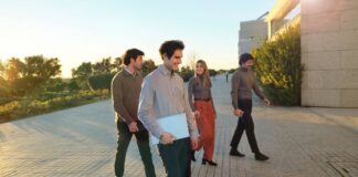 Imagen conceptual de jóvenes profesionales con portátiles y maletas en una terminal de aeropuerto, con el anuncio de Banco Santander de 400+ oportunidades laborales globales.