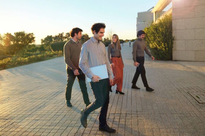 Imagen conceptual de jóvenes profesionales con portátiles y maletas en una terminal de aeropuerto, con el anuncio de Banco Santander de 400+ oportunidades laborales globales.
