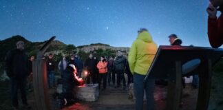 Grupo de personas realizando una observación astronómica nocturna bajo un cielo estrellado en las Muntanyes de Prades.
