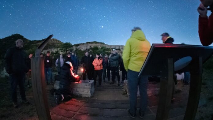 Grupo de personas realizando una observación astronómica nocturna bajo un cielo estrellado en las Muntanyes de Prades.
