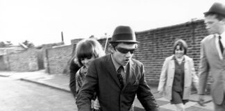 Jóvenes en scooter en una calle en blanco y negro durante los años sesenta.