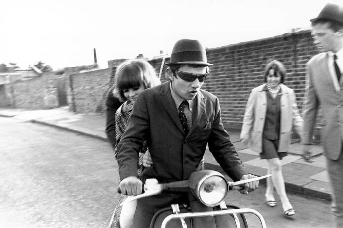 Jóvenes en scooter en una calle en blanco y negro durante los años sesenta.